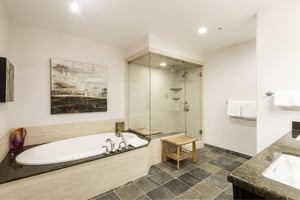 Main bathroom with slate tile floors, large jetted soaker tub, glass paneled shower door and steam shower