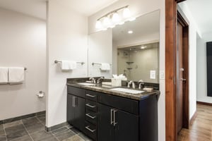 Main ensuite bathroom, dual vanity granite countertops with dark wood drawers and large frameless mirror