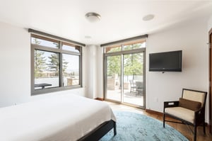Second bedroom with large picture window and a second set of sliding glass doors to access patio, wall mounted TV and accent chair