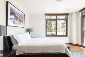 Second bedroom king bed draped in white linens and duvet, hardwood floors