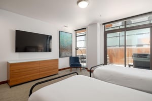 Guest bedroom with dedicated patio access via sliding glass doors, large flat screen wall mounted TV over double wooden dresser
