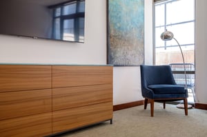 55 Flat screen TV in the guest bedroom with beautiful deep blue accent chair beneath a chrome finish floor arc lamp