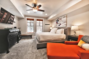 Main bedroom suite, king bed with white linen and tufted fabric bedframe and headboard, two large picture windows