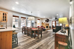 Kitchen breakfast bar leading out to the dining room and living room, south wall lined with picture windows