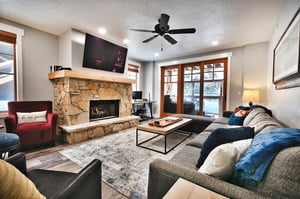 Hardwood floors in the living room with large area rug, flagstone hearth and wall mounted TV