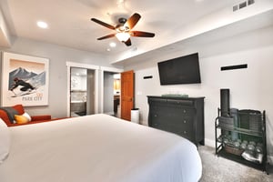 Luxurious king bed in the main bedroom, black wooden dresser and wall mounted flat screen TV