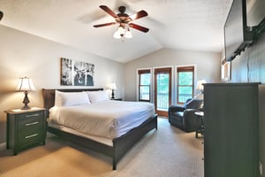 Main bedroom suite, glass patio door to private deck, vaulted ceiling and wooden blade ceiling fan, white duvet and king bed