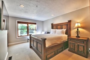 Guest bedroom with striking solid wood bedframe, queen bed and twin bed with large picture window