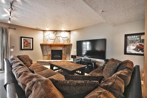 Den lounge with large sectional, 83 flat screen TV and flagstone fireplace wall