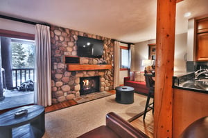 Living room has a gas fireplace with beautiful river rock surround