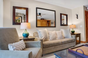 Living room includes a comfortable couch and chair with plenty of lighting