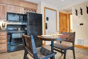 The dining area has seating for two around the pedestal table