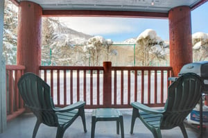 The private patio includes two green Adirondack chairs with views of the tennis courts