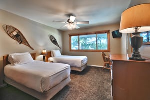 Second bedroom has two twinsized beds with white linen and ceiling fan