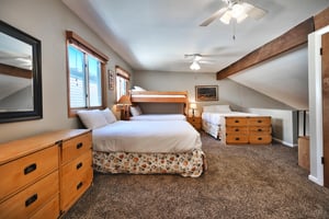 Loft area opens to the living room below. It has two ceiling fans, and plenty of storage with two wooden dressers