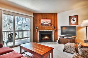 Living room with gas fireplace has wood paneling and tile surround to relax around after a day of skiing.