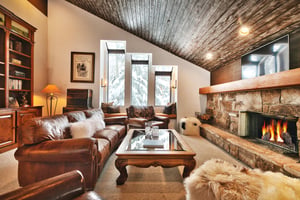 Beautiful living room with wooden beam ceiling, wood fireplace, and picture windows for abundant natural light