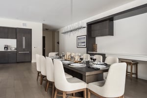 Generous solid wood dining table with seating for 10 in sloped arm upholstered high back chairs and wooden legs