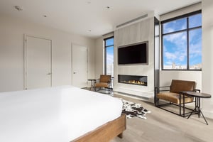 Main bedroom suite with two closets, leather accent chairs and tables next to the feature fireplace wall