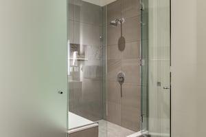 Tiled shower in the main bathroom with glass panel doors and chrome fixtures