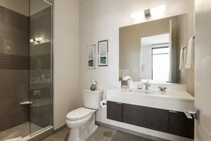 Ensuite guest bathroom with glass panel and dark tiled shower