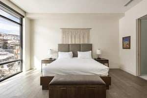 Final guest bedroom with boho woven wall art, hardwood floors, white walls and floor to ceiling windows