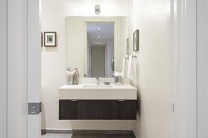 Hallway powder room with floating dark wood cabinet and white quartz counter