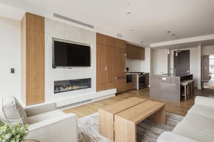 Open floor plan with living room, kitchen, and dining area, wooden and quartz accents, hardwood floors throughout, large flat screen TV mounted above the fireplace