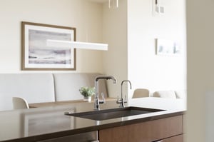 Kitchen island with chrome finishes and dining area in the background