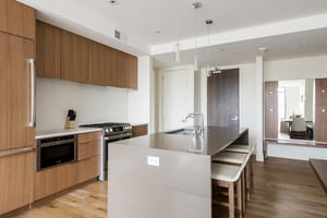 Fully equipped kitchen with dark and white quartz finishes, wood cabinetry and overlay refrigerator