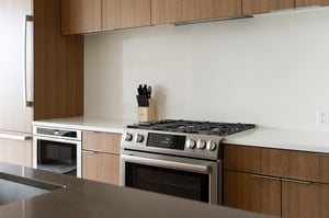 Chefs gas range in the kitchen with white quartz countertops and backsplash, wooden cabinets with chrome hardware
