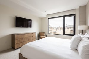 Wall mounted flat screen TV above the wooden dresser in the main bedroom with leather accent chair