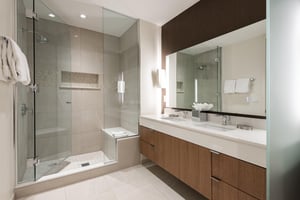 Ensuite main bath with two vanities, glass paneled shower door and tiled shower with bench