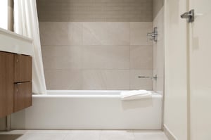Bath tub in the guest bathroom with chrome finishes and tiled wall