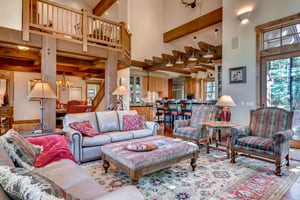 Welcoming open floor plan with high vaulted ceilings, hardwood floors, ornate area rugs, complete with two leather couches in the living room and two large armcharis