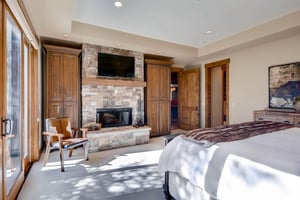 Main bedroom suite with wood burning fireplace, mounted flat screen TV, and cowhide accent chair