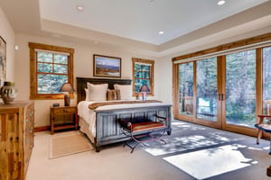 Luxurious king bed in the main suite with beautiful window walls and sliding doors to access private patio
