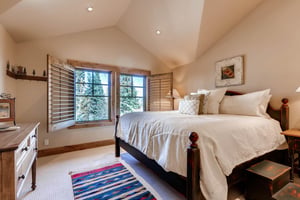 Graceful king bed in the third guest bedroom, wooden bedframe and large picture windows with wooden blinds