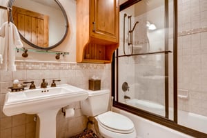 Full guest bathroom, porcelain pedestal sink and framed round bathroom mirror