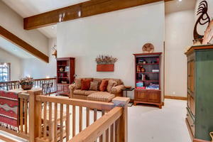 Gracious loft lounge with seating area, book shelves, and beautifully exposed wooden beams