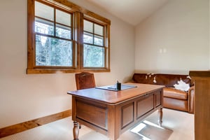 Elegant solid wooden desk in the loft are lit by large windows, cozy leather couch with cowhide decoration