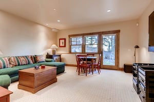 Comfy game room in the den with large green sectional couch and patio door for outdoor access