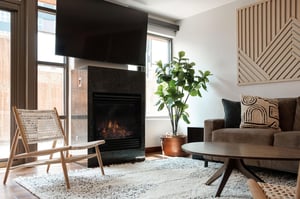 Cozy gas granite fireplace and 70 wall mounted TV in the living room with accent crosshatch chair