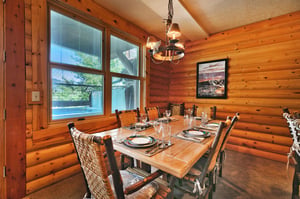 Pine wood walls encapsulate the dining area with solid wood table and rustic log style dining chairs