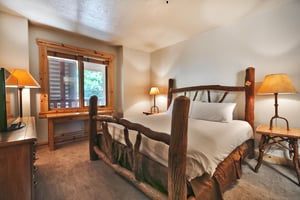 Second bedroom with log wood bedframe, large picture window with mountainside views
