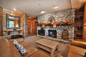 Gas fireplace in the river rock feature fireplace wall with flat screen TV and log mantle