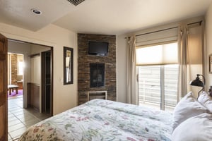 Sliding glass private balcony door in the bedroom, slatestone inroom fireplace and fireplace mounted flat screen TV