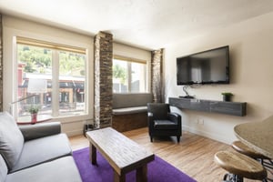 Living room overlooks Historic Main Street via two large picture windows, large wall mounted flat screen TV and hardwood floors