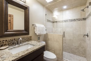 34 bathroom with tiled shower walls, glass shower door and river stone accent tiling, granite bathroom countertop, single vanity