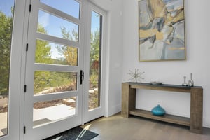 Vacation rental front door with glass windows to showcase the trees and mountains.
